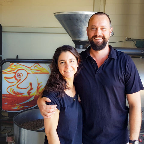 Fi and Lance from Sipping Duck with first logo and coffee roaster with coffee beans  in the background.