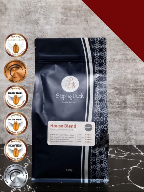Sipping Duck Specialty Coffee Roasters House Blend bag, blue with unique pattern. Golden bean and AICA award medals.