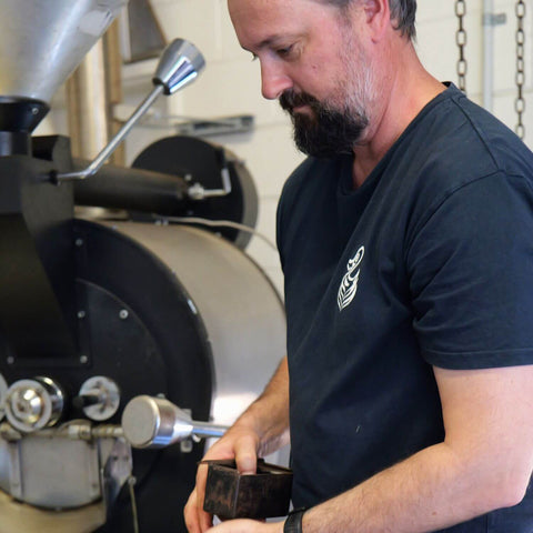 Lance from Sipping Duck Coffee Roasters during the destining process with coffee roaster in the background.