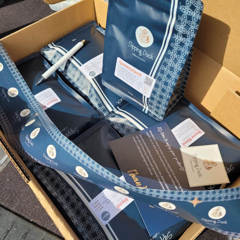 Sipping Duck bags of Queensland and House Blend coffee inside a box with thank you card, sticker, pen and tape with logo.
